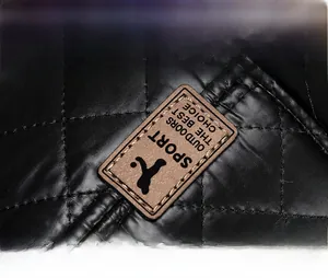 Detail of black quilted PU material with a brown leather Sport Outdoors logo patch