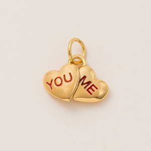 Close-up of gold double heart pendant with red engraved YOU and ME text details