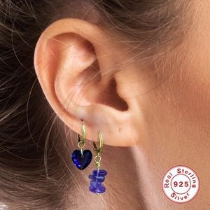 Detail of S925 silver hoop earrings with blue heart crystal and purple stone pendants