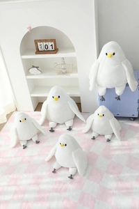 Multiple sizes of plush white seagull dolls with yellow beaks displayed on a shelf