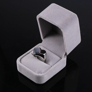 Macro view of polished stainless steel heart ring showcased in a grey velvet jewelry box