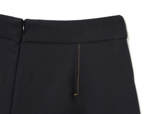 Détail de la taille avec fermeture éclair invisible et coutures contrastées sur tissu noir