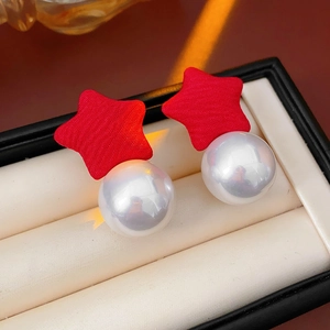 Detailed close-up of star ear studs with red fabric and large white pearls in a jewelry box