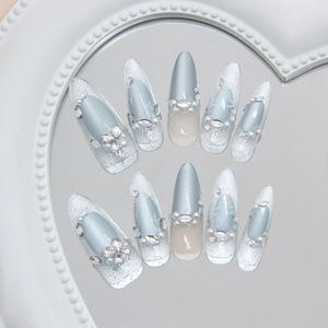 Glacier blue cat-eye press-on nails with white lace patterns and pearl rhinestone accents