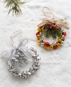 Close-up of red and gold Christmas bells with burlap bow and greenery on snow