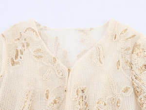Detail of V-neckline featuring golden sequin floral embroidery on beige mesh fabric