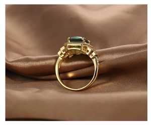 Macro detail of a vintage gold ring with a square green gemstone on brown silk