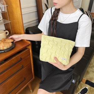 Detailed view of yellow quilted makeup bag with woven label in a cozy home setting
