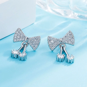 Detail of silver bow earrings with sparkling cubic zirconia drops on elegant silk
