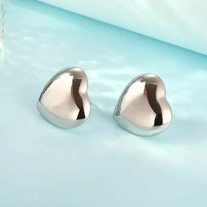 Macro view of 3D heart-shaped silver earrings with mirror-like polished finish