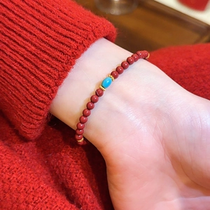 Nahaufnahme eines roten Achatperlenarmbands mit einer türkisfarbenen Perle am Handgelenk