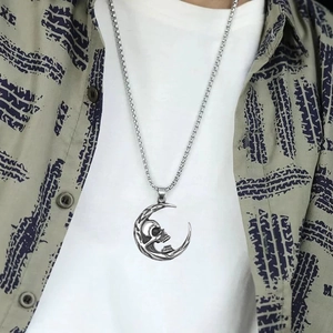 Detailed view of silver skull moon pendant necklace worn over a printed street style shirt