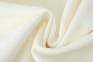 Nahaufnahme von cremeweißem Wollstoff mit weicher Textur und feiner Faserstruktur