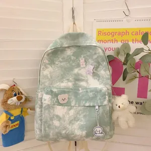 Detail of green and white tie-dye canvas backpack with cute plush bear and dog charms