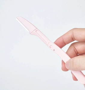 Close-up of pink folding eyebrow razor with protective microblade for makeup grooming