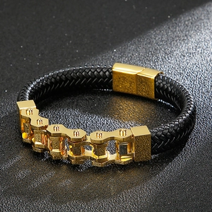 Close-up of gold motorcycle chain links on a black braided leather bracelet for men