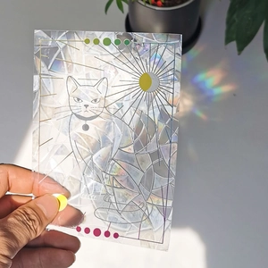 Close-up of a cat-shaped rainbow suncatcher window film showing prism light effects
