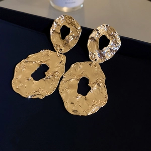 Macro shot of gold-plated geometric earrings with vintage hammered texture and hollow design