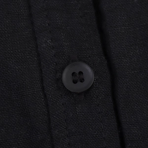 Gros plan sur un bouton noir à quatre trous sur le tissu en lin de la robe dos nu