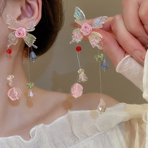 Détail de boucles d'oreilles ailes de papillon avec roses et glands en perles colorées