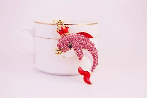 Detail of pink rhinestone dolphin keychain with gold crown and red enamel accents