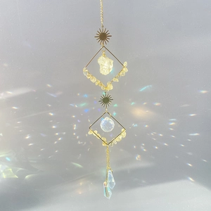 Crystal suncatcher with raw citrine stones and prisms casting rainbow light on white background