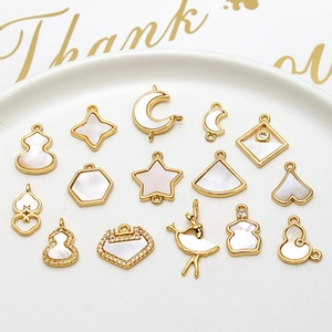 Detailed view of assorted gold-plated charms with shell inlay and cubic zirconia crystals