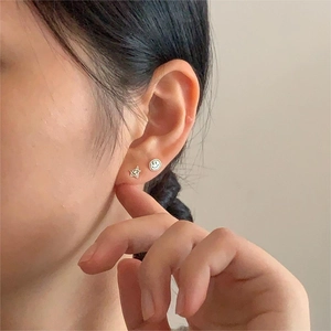Close-up of minimalist 925 silver smiley and star earrings worn by a female model