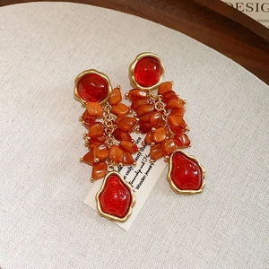 Close-up of vintage flower tassel earrings with red stones and orange resin chips