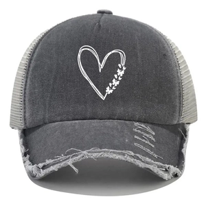 Close-up of distressed heart and butterfly print on washed grey denim trucker cap