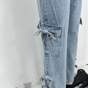 Detail of light blue denim cargo pants showing a side pocket with a stylish denim bow knot