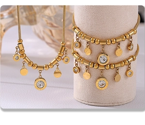 Detail of gold-plated chain necklace and bracelet set with round charms and zircons