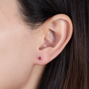 Close-up of a S925 silver gold-plated stud earring with a red zircon on a model ear