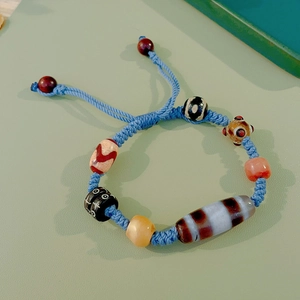 Detailed close-up of handmade woven blue rope bracelet with multi-color beads