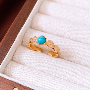 Detail of 18k gold plated tiger eye ring with turquoise stone in a velvet jewelry box