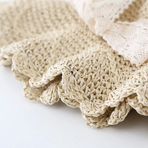 Close-up of beige straw weave texture with delicate lace trim on sun hat edge