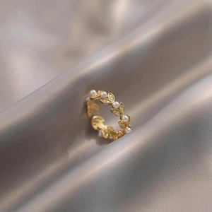 Detailed macro view of golden leaf ring with pearls and zircons on silk fabric