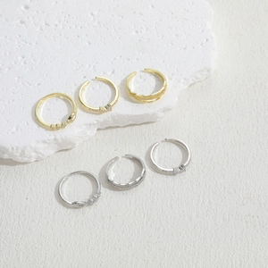 Minimalist geometric bow open rings with zircons in gold and silver set on stone