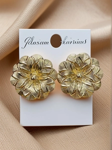 Close-up of golden floral earrings with detailed texture on elegant silk background