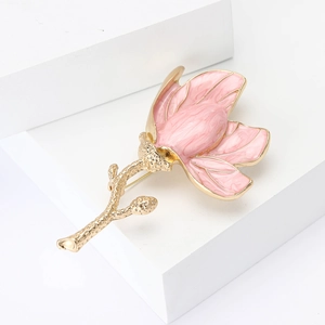 Elegant pink enamel magnolia flower brooch with golden stem on white artistic blocks