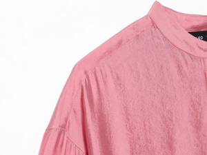 Detail of pink satin blouse featuring a refined stand collar and delicate shoulder stitching