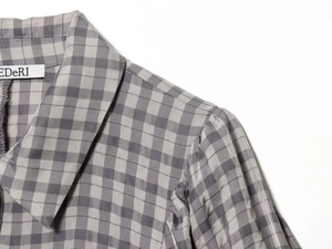 Detail shot of the grey plaid dress neckline and shoulder with brand label