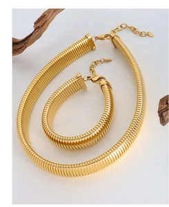 Detail of gold snake chain necklace and bracelet set on a natural wood block