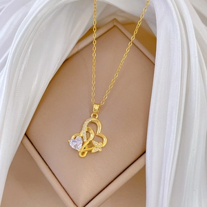 Gros plan sur les pendentifs cœurs dorés entrelacés avec zircon et fond en soie douce