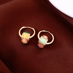 Detailed macro of two-tone flower earrings with cat-eye beads on brown fabric