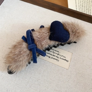 Detail of plush brown claw clip with navy velvet bow and heart on textured background