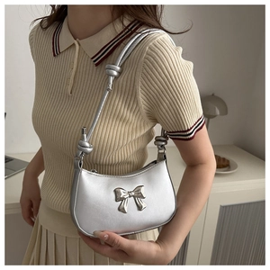 Detail of silver bow shoulder bag with knotted strap and smooth metallic finish