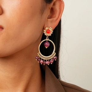 Detail view of ethnic boho earrings with purple beads and gold circle on model