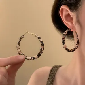 Close-up of leopard print fabric hoop earrings worn for a stylish fashion statement