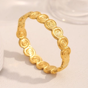 Macro detail of 18K gold plated stainless steel bangle with spiral textured pattern
